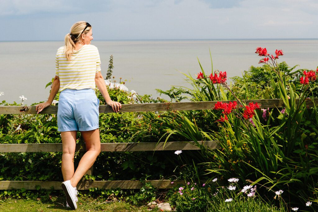 A woman looking over a fence at the sea.