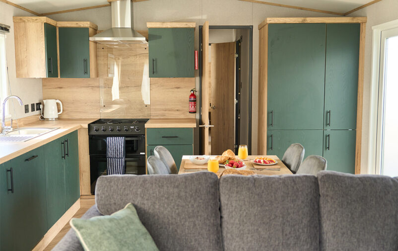Contemporary kitchen in a luxury holiday home with green cabinets and wooden accents.