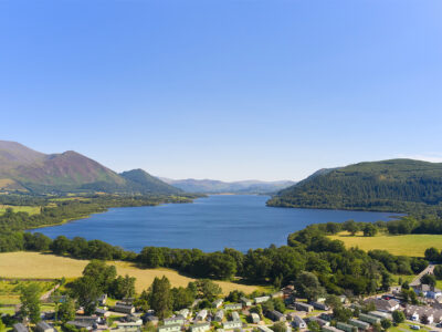 Beautiful lake surrounded by green hills and a small village in the foreground.