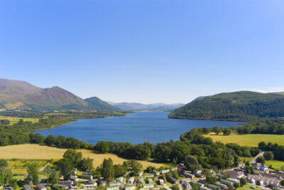 Beautiful lake surrounded by green hills and a small village in the foreground.