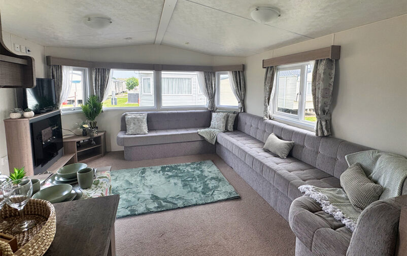 Spacious living room with large windows and comfortable grey sofas at Lovat Parks.