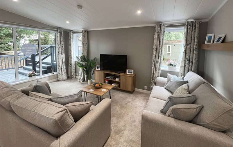 Comfortable living room with sofas, TV, and large windows at Victory Wisteria Lodge.