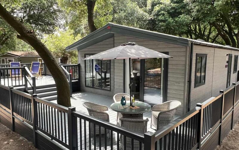 Modern lodge with outdoor seating and umbrella at Lovat Parks.