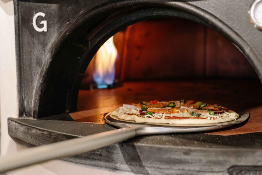 Pizza going into an oven.