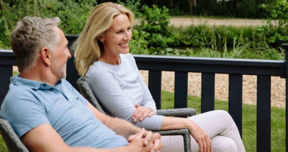 A couple sitting on the decking of a caravan.