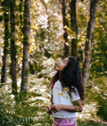 A child staring up at the trees.