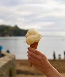 Someone holding an ice cream in front of the sea.