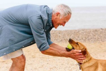 A man with his hands around his dogs face, affectionately.