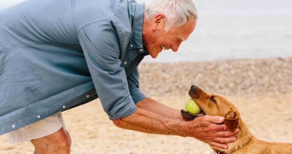 A man with his hands around his dogs face, affectionately.