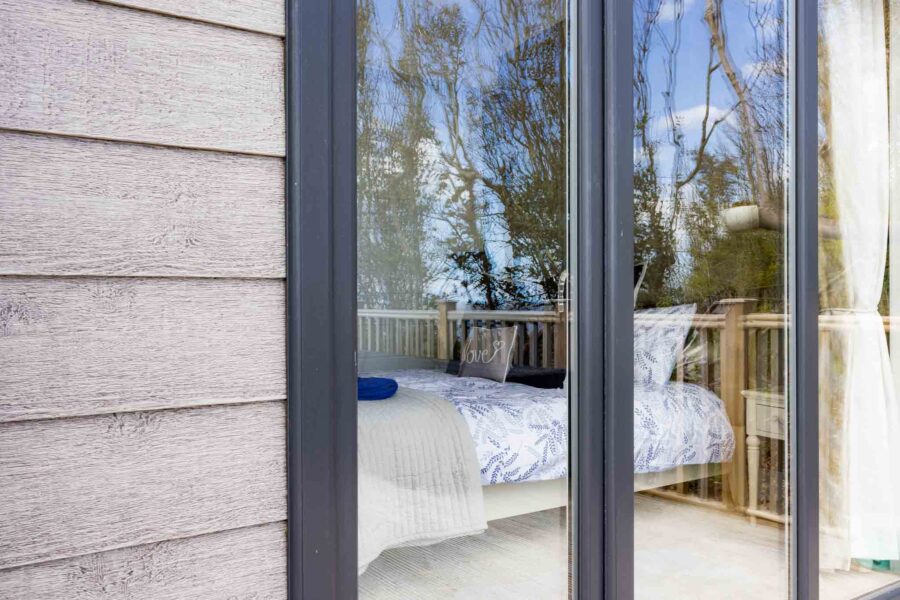 The outside of a lodge showing a bedroom through the glass.