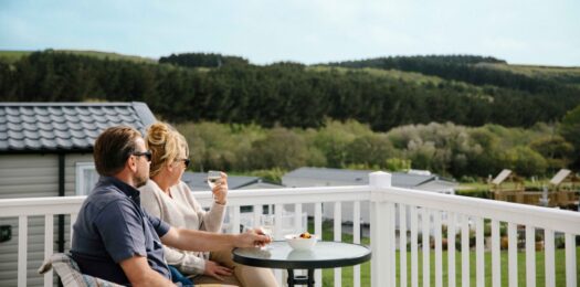 A couple sitting on the decking a lodge.