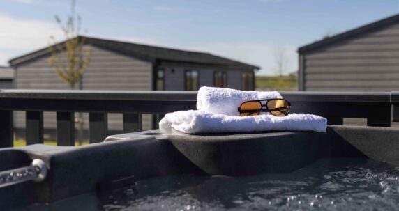 Glasses and a towel on th edge of a hot tub.